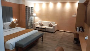 A hotel room with a bed, a sofa, a small table, and a bench. - Hotel Park Square  (Purnia)