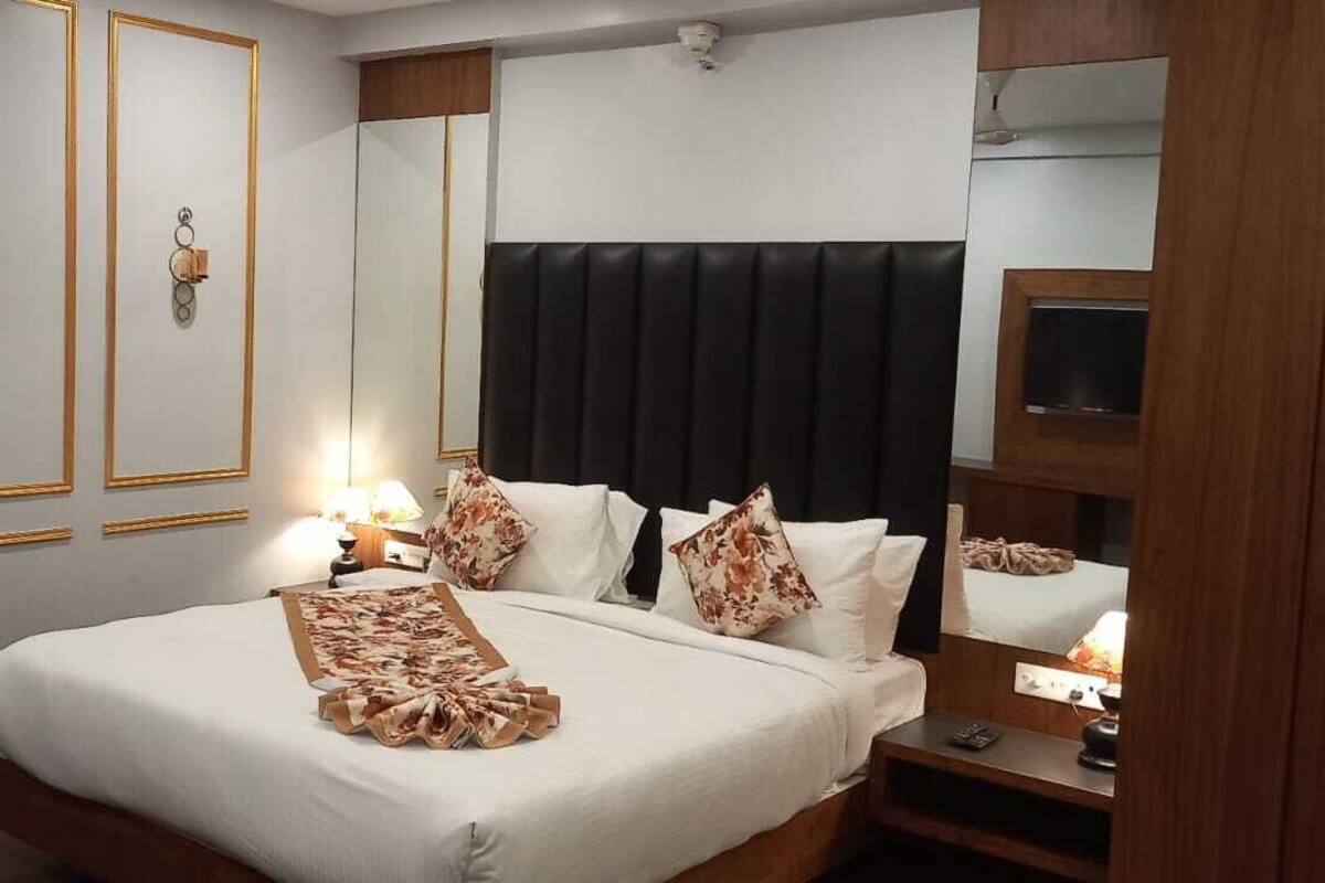 A hotel room with a large bed, a chair, a mirror, and a wall decoration.