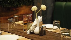 A dining table set with plates, glasses, and a menu. - Hotel Park Square  (Purnia)