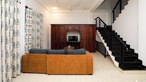 A living room with a brown sofa, a TV, wooden cabinets, and a staircase. - Zara Home (Galle)