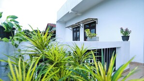 A modern building with a white exterior, large windows, and potted plants on the balcony. - Zara Home (Galle)