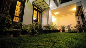 A modern building with large windows and a well-maintained garden area with potted plants. - Zara Home (Galle)