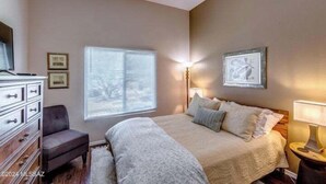 A bedroom with a bed, a dresser, a chair, a window with blinds, and wall-mounted lamps. - Breathtaking views of the Catalina and Rincon Mountains in this 2nd floor (Tucson)