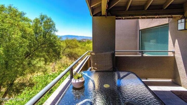 A balcony with a glass table, a potted plant, and a view of greenery and distant hills. - Breathtaking views of the Catalina and Rincon Mountains in this 2nd floor (Tucson)
