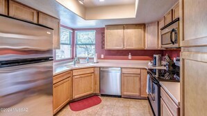 A modern kitchen with wooden cabinets, a stainless steel refrigerator, a dishwasher, a microwave, and a gas stove. - Breathtaking views of the Catalina and Rincon Mountains in this 2nd floor (Tucson)
