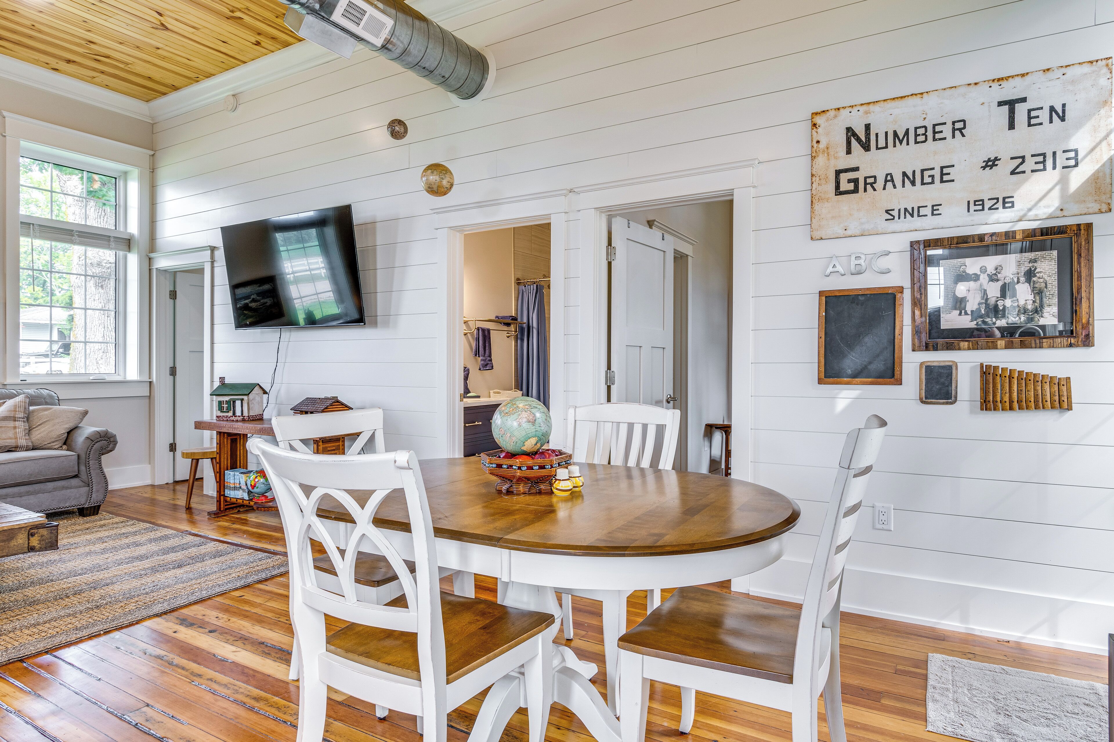 A dining area with a wooden table and white chairs, a globe, and a vintage sign on the wall.