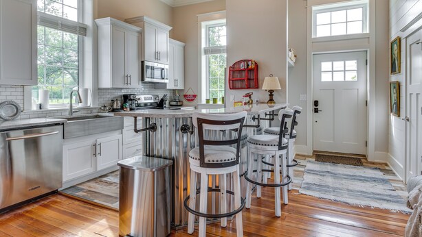 A kitchen with white cabinets, stainless steel appliances, and a bar area with stools. - West Lafayette Home ~ 3 Mi to Purdue Campus! (West Lafayette)