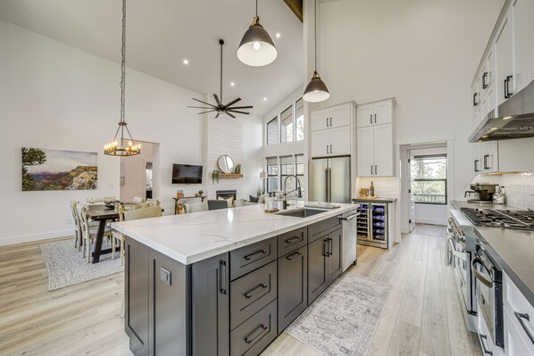 A modern kitchen with a large island, stainless steel appliances, and pendant lighting.