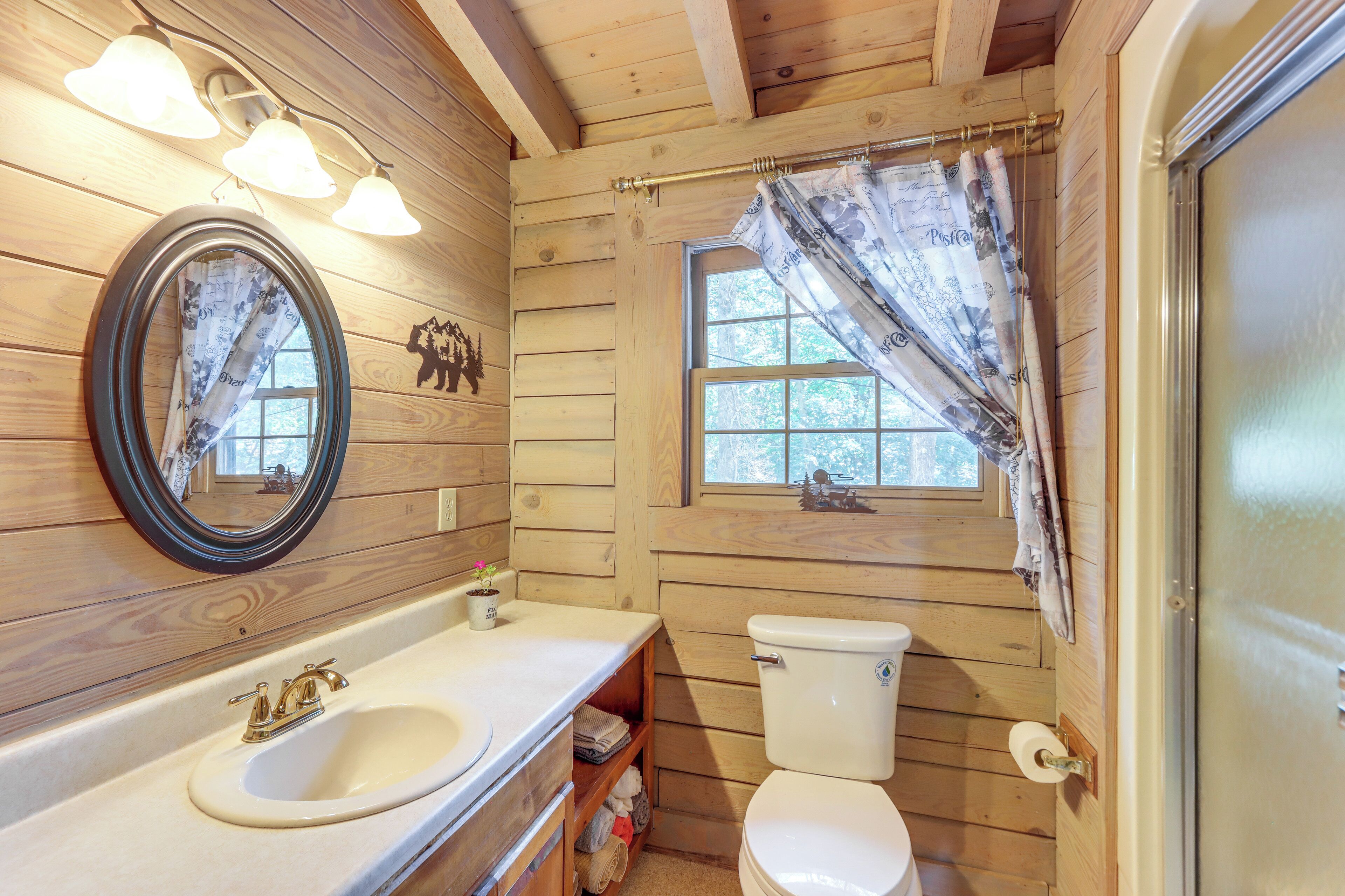 Un baño de cabaña de madera con lavamanos, inodoro y ventana.