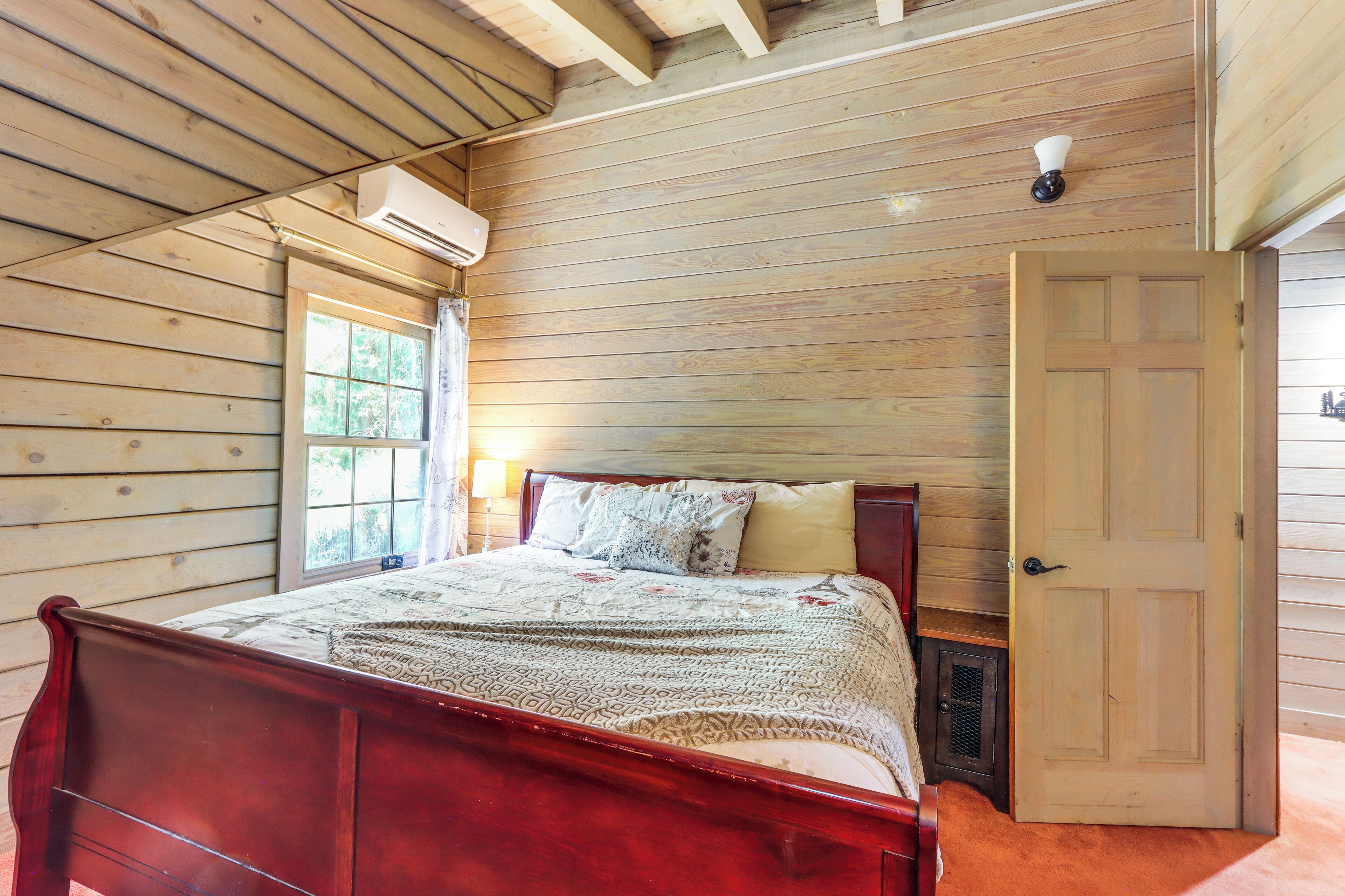 Un dormitorio con paneles de madera, una cama, una puerta y un equipo de aire acondicionado.