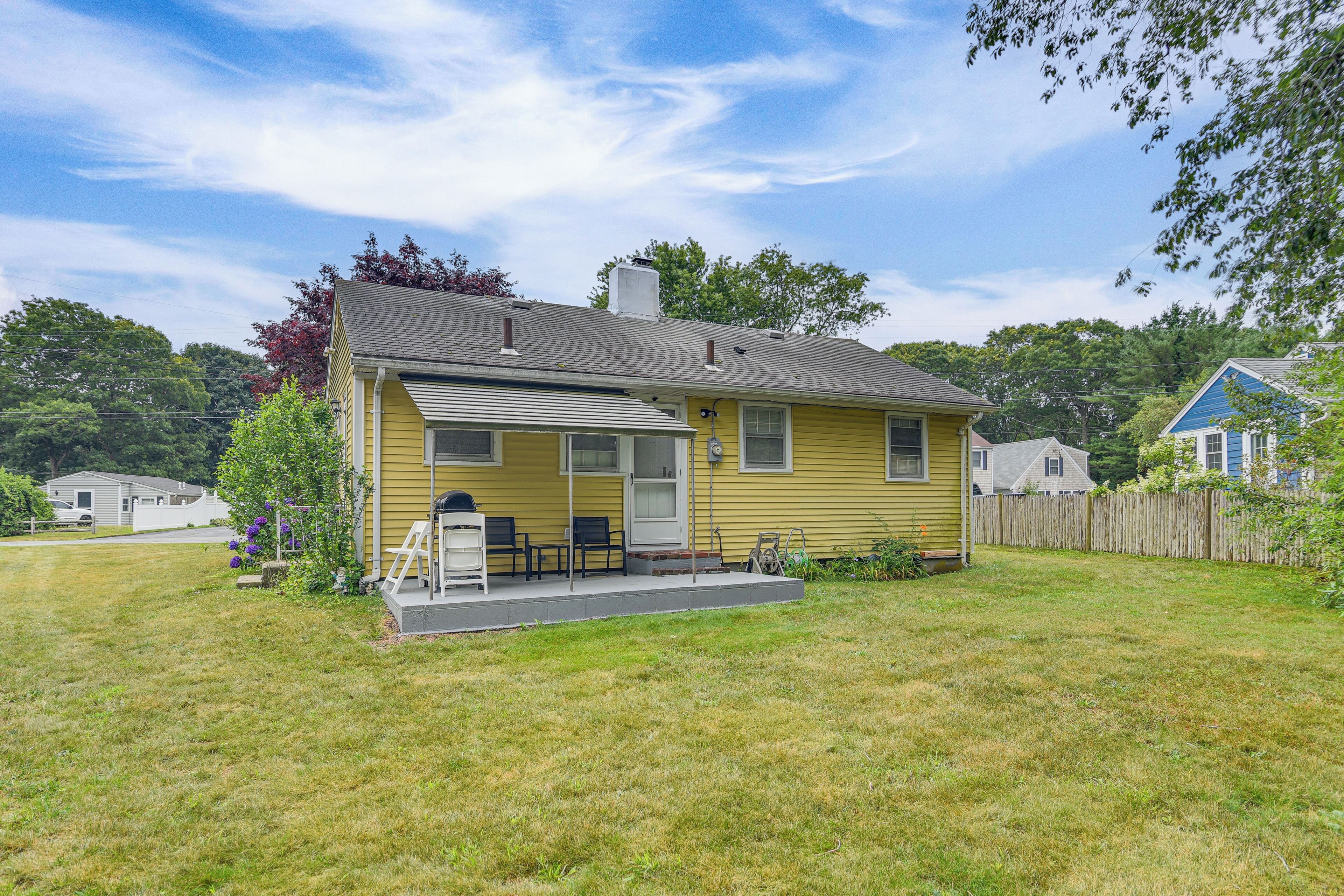 A yellow single-story house with a front porch, a small attached garage, and a well-maintained lawn.