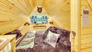 Een knus houten interieur van een vakantiehuisje, ingericht met berenmotieven, waaronder een berenhoofd aan de muur en kussens in de vorm van beren.