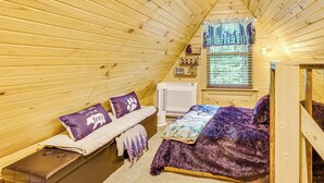 Een knus kamer in een blokhut met een bed, een bankje en een raam met jaloezieën.