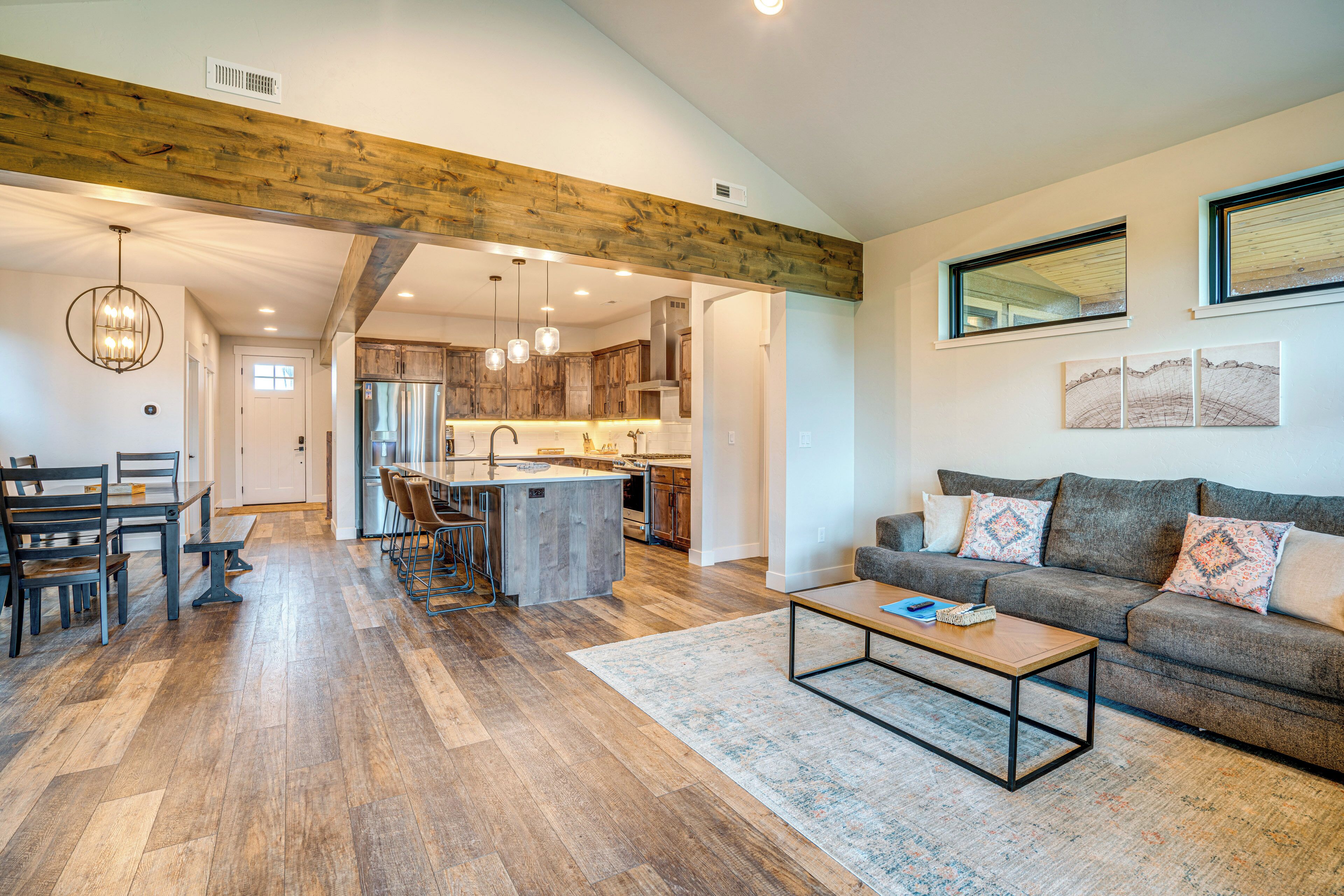 A spacious living area with a wooden floor, a sofa, a coffee table, and a kitchen in the background.