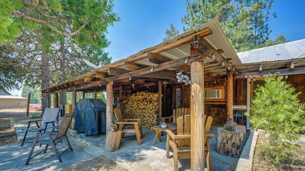 A rustic outdoor seating area with wooden chairs and tables, a covered patio, and a stack of firewood. - Rustic Cabin w/ Patio: 8 Mi to Kings Canyon Park (Miramonte)