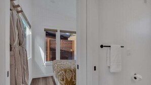 A bedroom with a bed, a window, a door, and a towel rack.