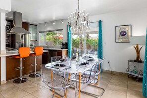 Une cuisine moderne avec un coin repas, comprenant une table ronde, des chaises et un lustre.