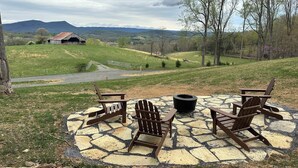 A patio with Adirondack chairs and a fire pit, overlooking a rural landscape with hills and a barn. - Log cabin with mountain VIEWS in Lexington! Near VA Horse Ctr, 8 mi from VMI/W&L (Lexington)