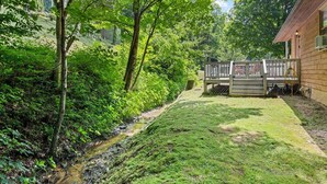 A wooden cabin with a grassy yard and a small stream. - Sunset Creek-Pets Welcome, Motorcycle Friendly (Maggie Valley)