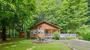 A wooden cabin with a porch, surrounded by a well-maintained lawn and trees. - Sunset Creek-Pets Welcome, Motorcycle Friendly (Maggie Valley)