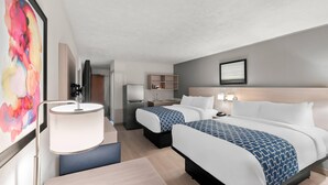 Een hotelkamer met twee bedden, een bureau, een stoel, een lamp, een schilderij en een klein plankje met spullen.