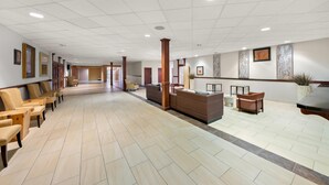 Een ruime lobby met een receptiebalie, een zithoek en een gang naar andere kamers.