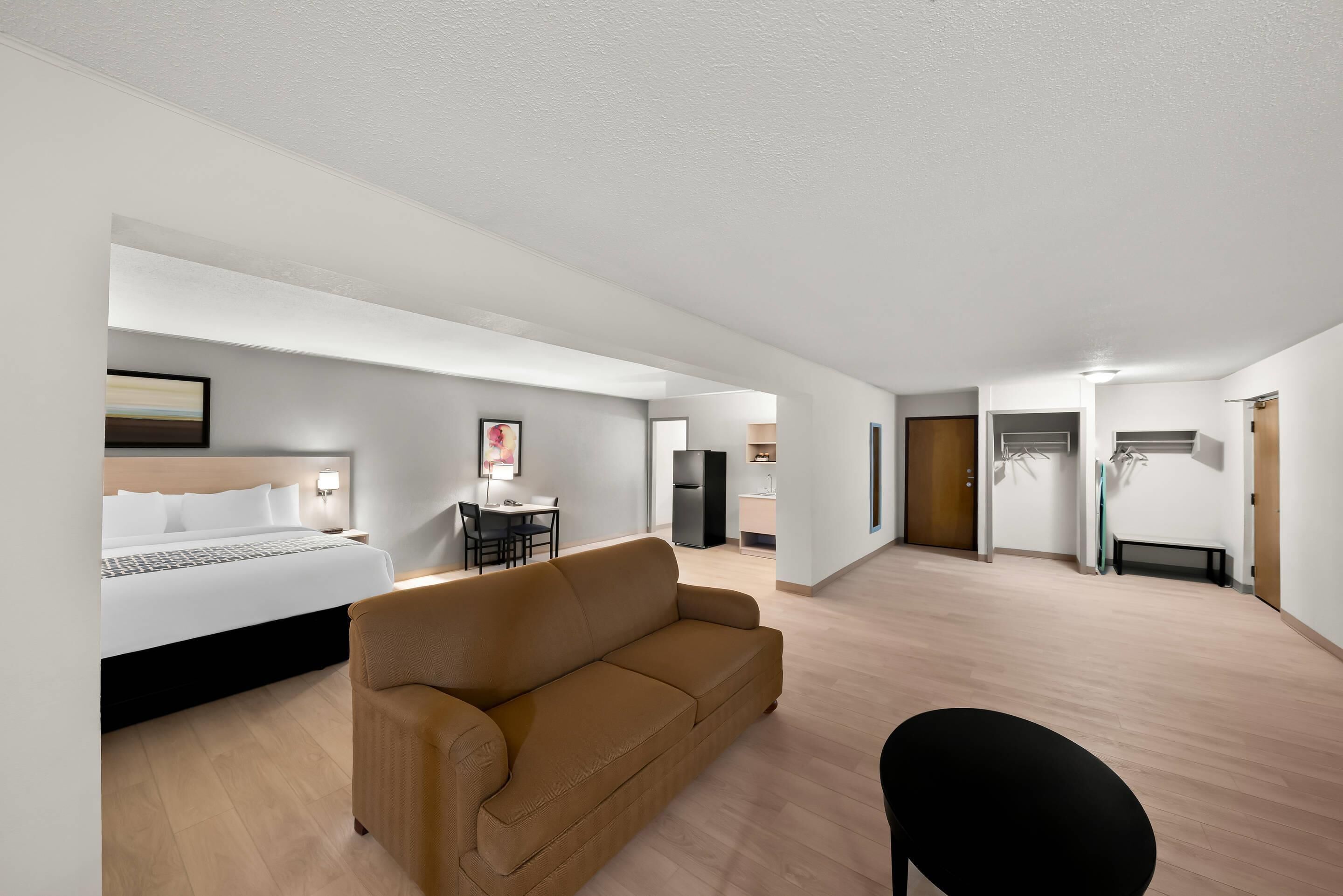 Une chambre d’hôtel moderne équipée d’un lit, d’un canapé, d’une table à manger et d’un coin cuisine.