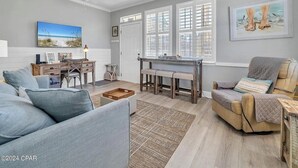 A living room with a sofa, a chair, a desk, and a piano.