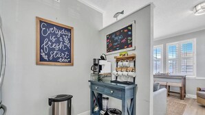 A kitchen with a coffee station, a trash can, and a chalkboard with motivational writing.