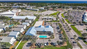 An aerial view of a commercial area with multiple buildings, parking lots, and a swimming pool.