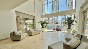 A spacious living area with a high ceiling, large windows, and modern furniture. - Apartamento Navy 2 habitaciones (Cartagena)