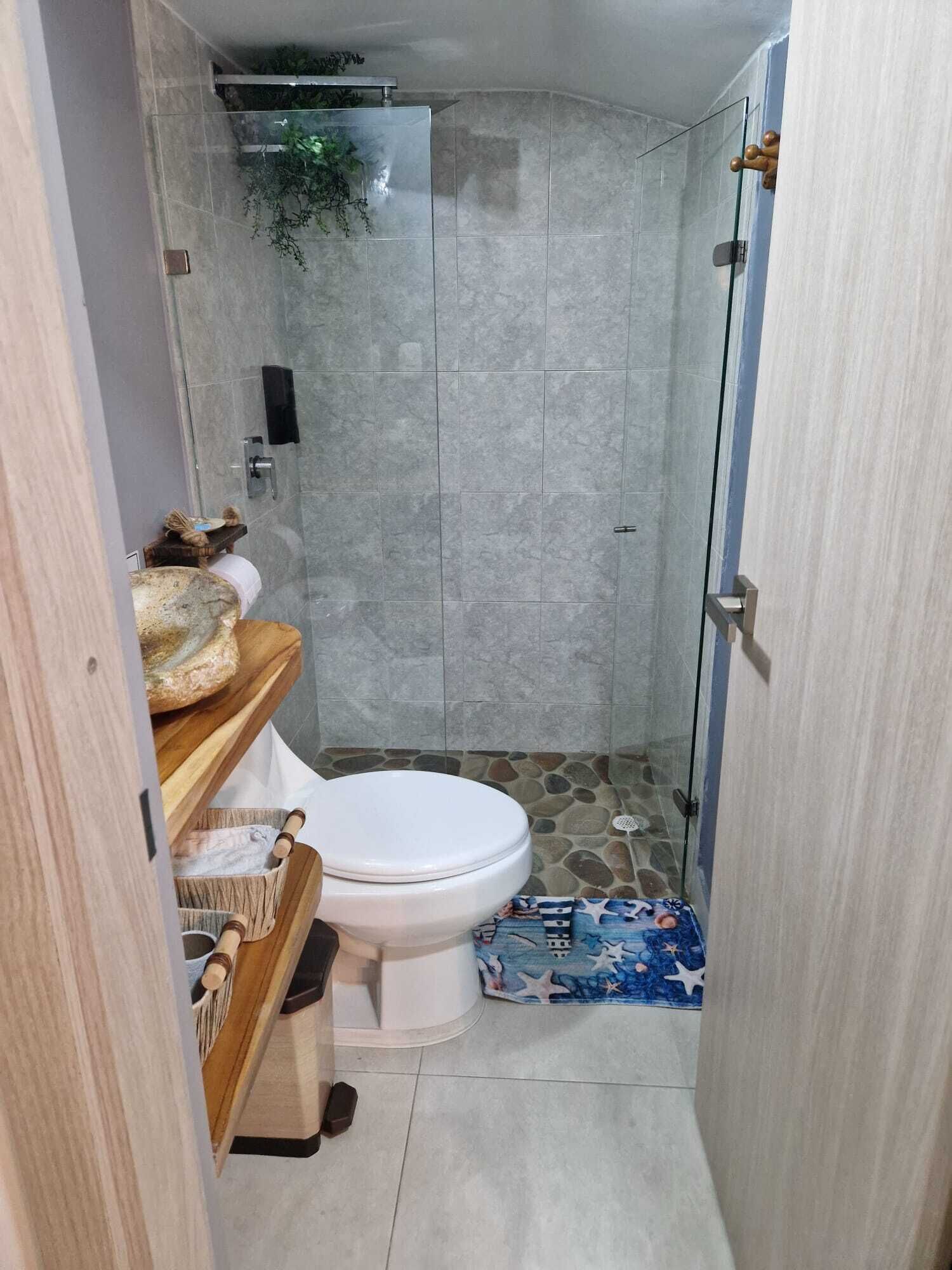 A compact bathroom with a toilet, shower, and a small sink area.