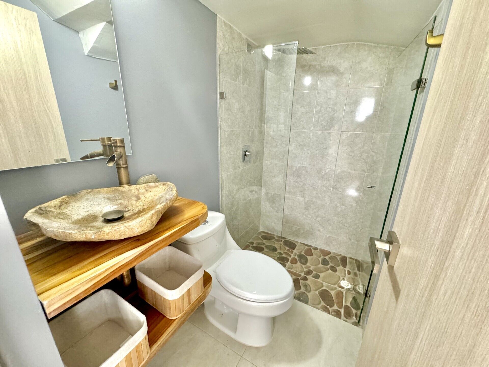 Een badkamer met een wastafel van steen, een toilet en een douchehoek.