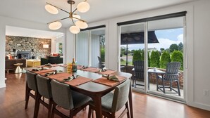 Un espace repas comprenant une grande table, des chaises et un lustre moderne.