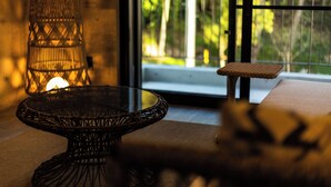 A wicker table with a glass top in a room with a large window, a wicker lamp, and a small bench. - RYUKYU BREEZE (Nago)