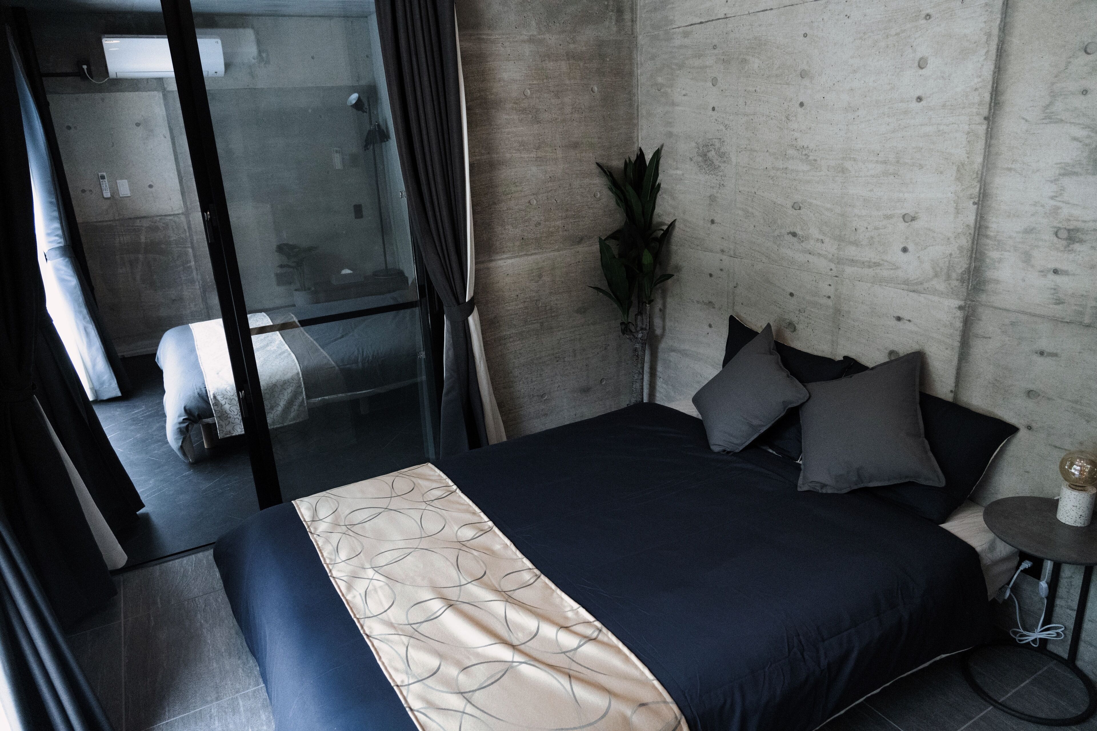 A modern bedroom with a large bed, a small round table, and a potted plant.