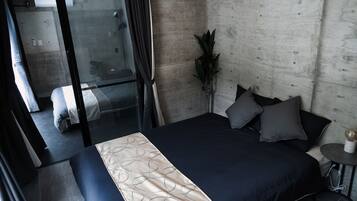 A modern bedroom with a large bed, a small round table, and a potted plant.