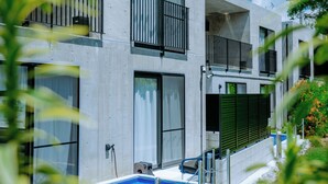 A modern building with a pool, balconies, and a clear sky. - RYUKYU BREEZE (Nago)