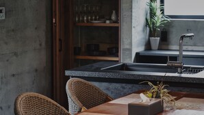 A modern kitchen with a black countertop, stainless steel sink, and a potted plant. - RYUKYU BREEZE (Nago)