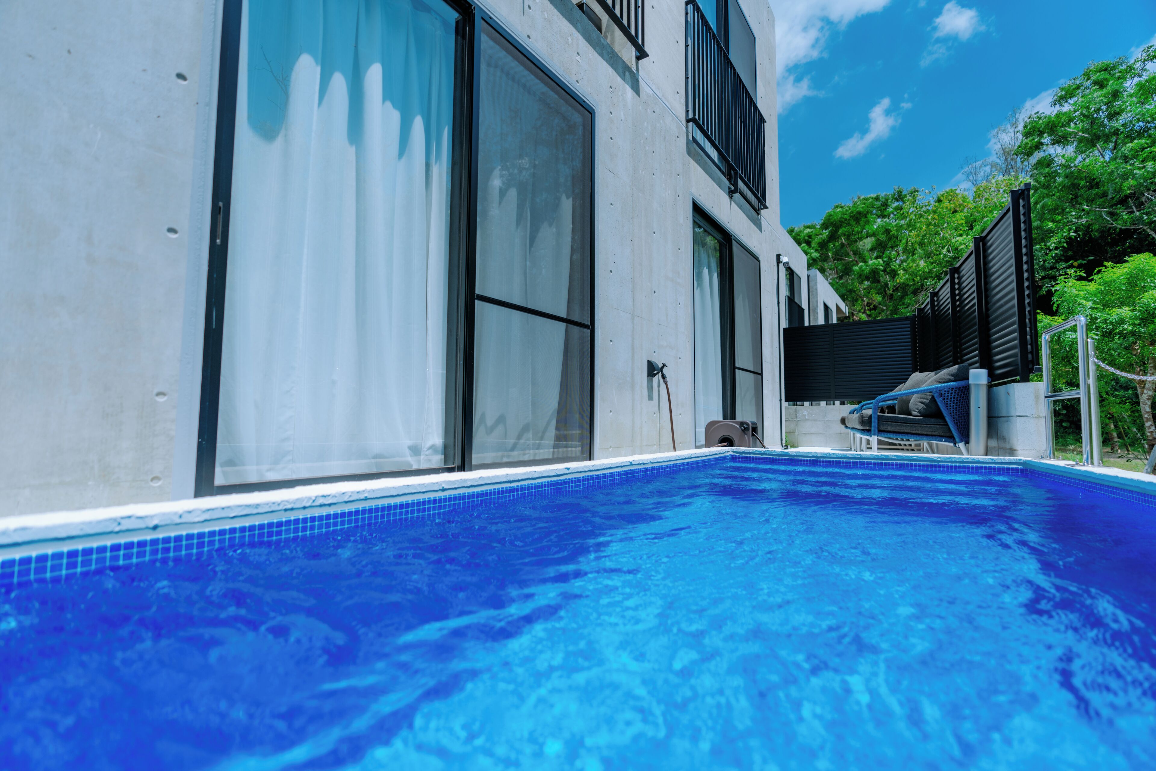 A modern building with a swimming pool, large windows, and a balcony.