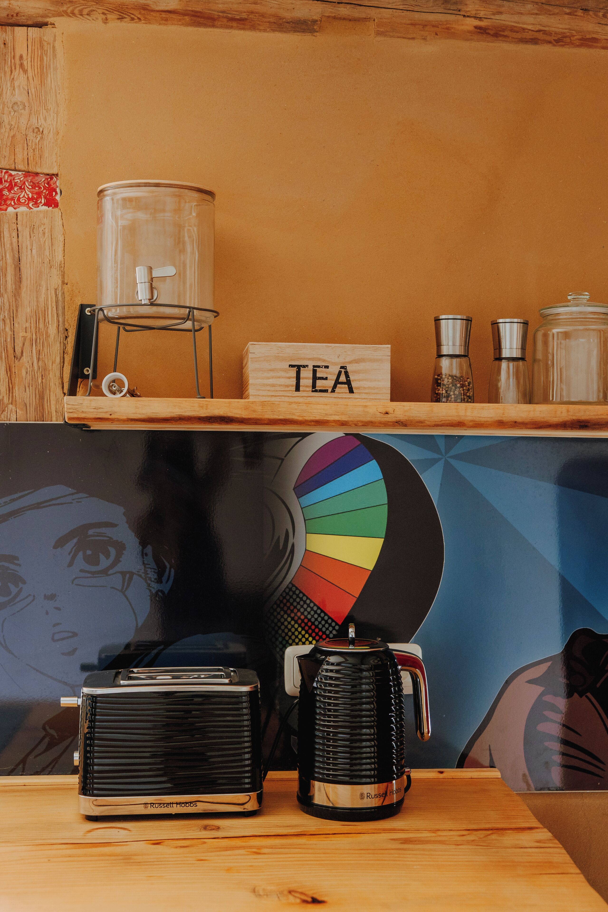 Une étagère en bois ornée d’une enseigne représentant une tasse de thé, d’une roue colorée et d’anciens appareils électroménagers.