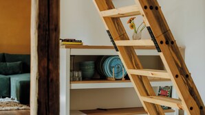 A wooden ladder leaning against a white shelving unit with books and decorative items. - Vacation apartment Linda (Ilmenau)
