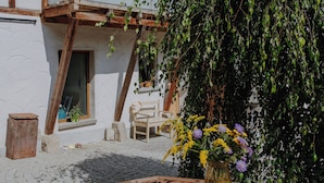 A wooden table with a pitcher and glasses, a wooden bench, and a white building with wooden beams and a balcony. - Vacation apartment Linda (Ilmenau)