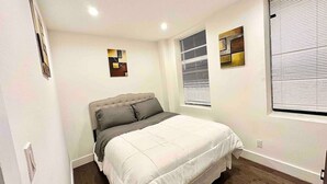 A bedroom with a bed, a window with blinds, and a wall-mounted artwork. - Prime soho 2 bedroom (New York)