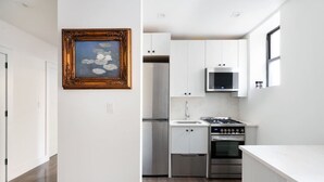 A modern kitchen with white cabinetry, stainless steel appliances, and a wooden floor. - Prime soho 2 bedroom (New York)