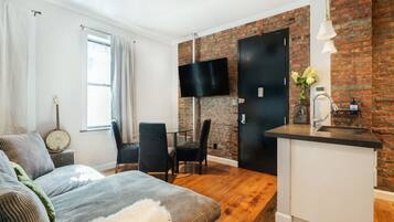 Un espacio habitable compacto con área de cocina, una mesa de comedor y un sofá.