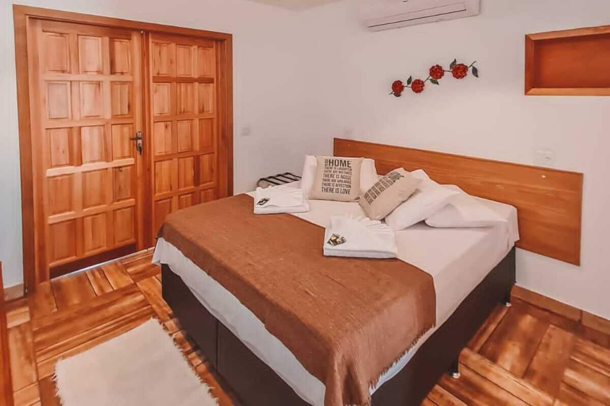 Un dormitorio con una cama de madera, un armario grande de madera, un ventilador de techo y un aire acondicionado instalado en la pared.