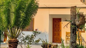 Un bâtiment à deux étages, doté de nombreuses fenêtres et portes, entouré d’une végétation luxuriante et d’une pelouse bien entretenue.