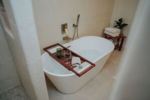 Un baño moderno con una bañera independiente, un perchero y una pequeña planta.