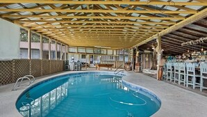 Une piscine intérieure avec un plafond en bois et une table de billard.
